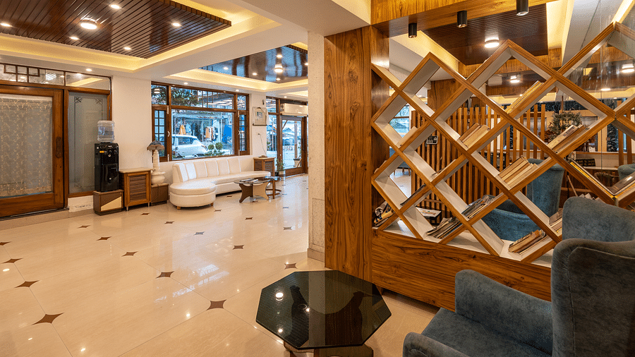 The lobby of DLS Meghavan Resort with comfortable seating, a reception desk, and decorative wooden partitions.